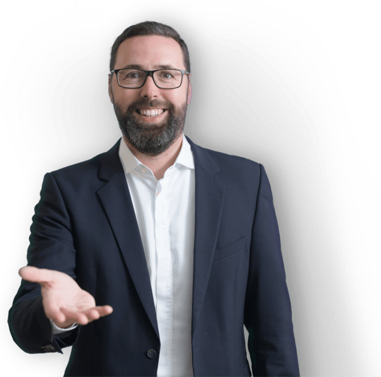Porträt von Geschäftsführer Matthias Thürling, einem Mann mittleren Alters mit Bart und Brille, der lächelnd eine Hand ausstreckt, als ob er zur Begrüßung die Hand schütteln möchte. Er trägt einen dunkelblauen Anzug und ein weißes Hemd ohne Krawatte. Der Hintergrund ist transparent.